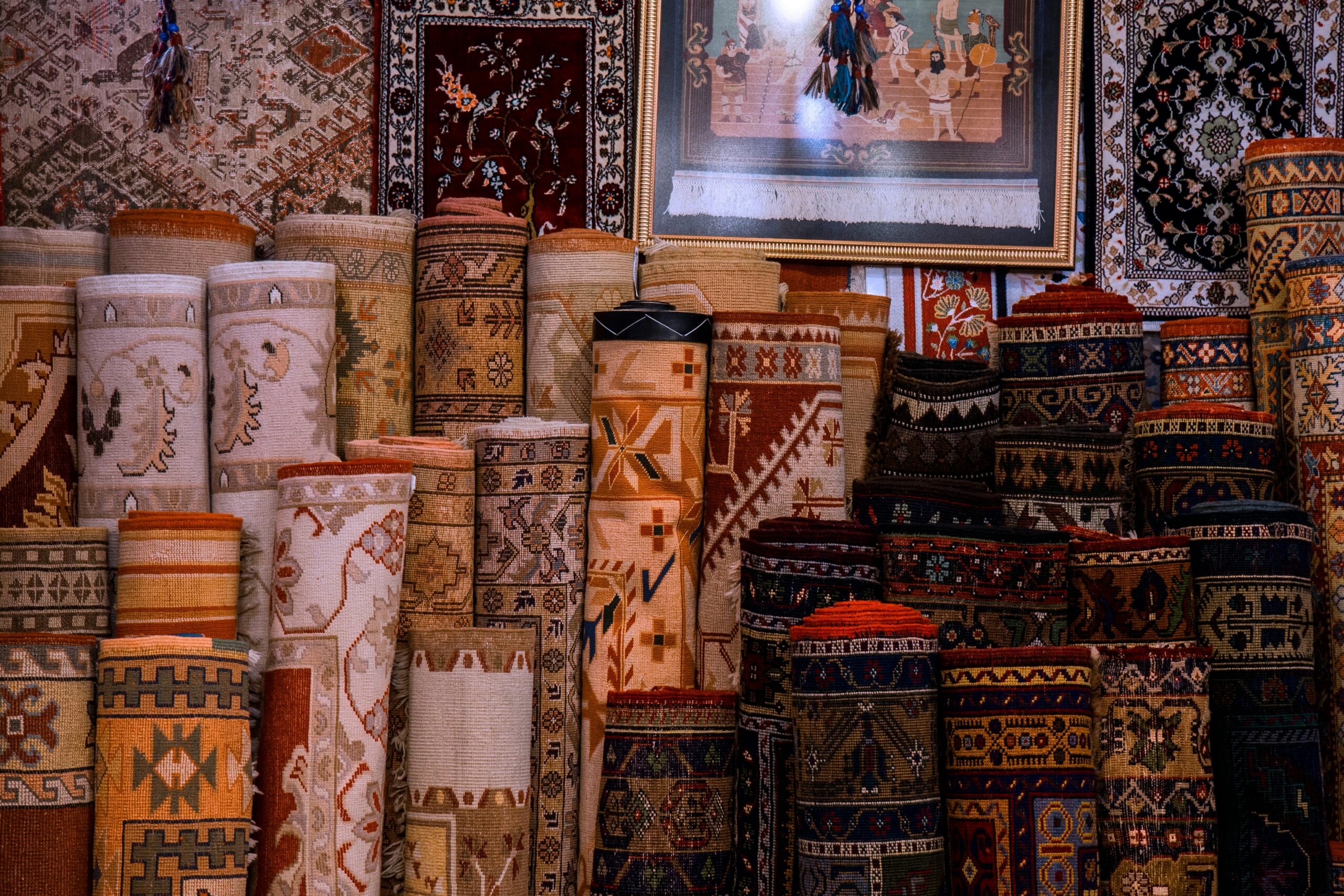 Vibrant collection of traditional rolled carpets on display in a cultural bazaar setting.
